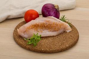 Raw chicken breast on wooden board and wooden background photo