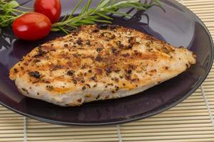 Grilled chichen breast on the plate and wooden background photo