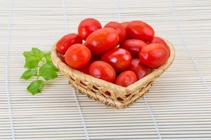 Cherry tomato in a basket on wooden background photo