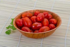 Cherry tomato in a bowl on wooden background photo