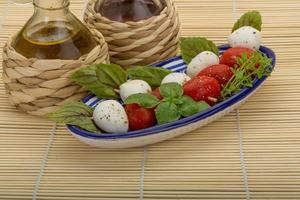 Caprese salad in a bowl on wooden background photo