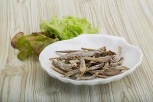 Dries anchovy in a bowl on wooden background photo