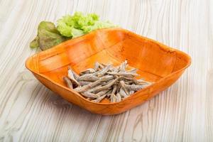 Dries anchovy in a bowl on wooden background photo