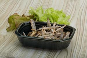 Dries anchovy in a bowl on wooden background photo
