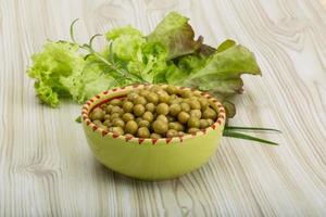 Marinated peas in a bowl on wooden background photo