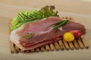 Prosciutto on wooden board and wooden background photo