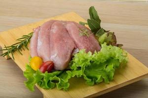 Raw pork schnitzel on wooden board and wooden background photo