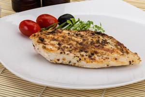 Grilled chichen breast on the plate and wooden background photo