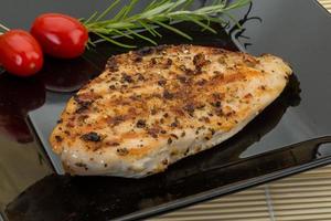 Grilled chichen breast on the plate and wooden background photo