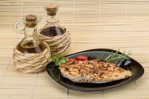 Grilled chichen breast on the plate and wooden background photo