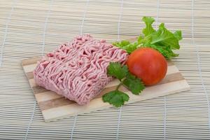 Raw minced pork meat on wooden board and wooden background photo