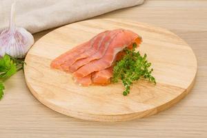 Sliced salmon on wooden board and wooden background photo