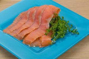 Sliced salmon on the plate and wooden background photo