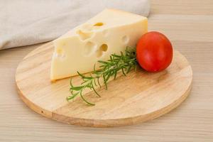 queso maasdam sobre tablero de madera y fondo de madera foto