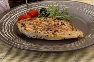 Grilled chichen breast on the plate and wooden background photo