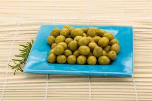 Green olives in a bowl on wooden background photo