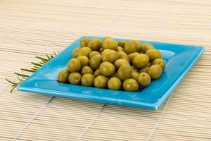 Green olives in a bowl on wooden background photo