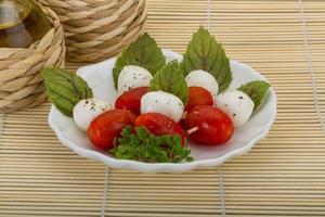 ensalada caprese en el plato y fondo de madera foto