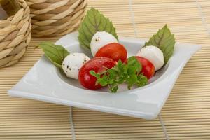 ensalada caprese en el plato y fondo de madera foto