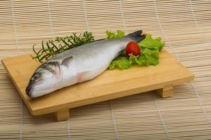 Raw seabass on wooden board and wooden background photo