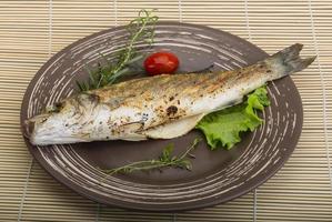 Grilled seabass on the plate and wooden background photo