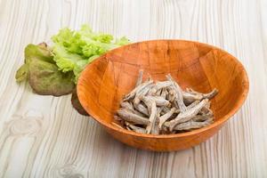 Dries anchovy in a bowl on wooden background photo