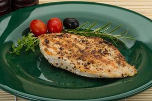 Grilled chichen breast on the plate and wooden background photo