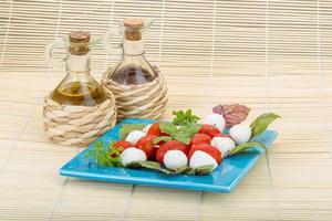 Caprese salad on the plate and wooden background photo