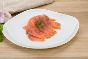 Sliced salmon on the plate and wooden background photo