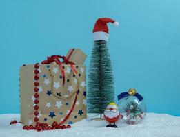 una bolsa de papel con regalos junto al árbol de navidad. juguetes de navidad en la nieve. Feliz Navidad. foto