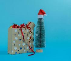 A paper bag filled with gifts next to a Christmas tree. Merry Christmas. photo