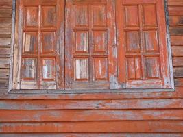 Three old wooden windows with brown paint are peeling. photo