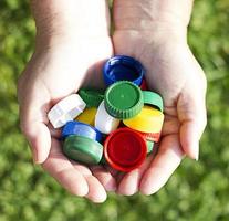 plastic colored corks in hands on a background of grass.  ecology concept photo