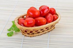 Cherry tomato in a basket on wooden background photo