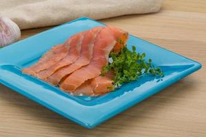 Sliced salmon on the plate and wooden background photo