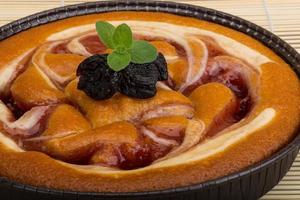 Plum cake in a bowl on wooden background photo