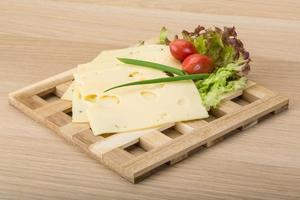 Maasdam cheese on wooden board and wooden background photo