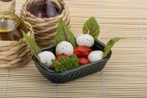 Caprese salad in a bowl on wooden background photo