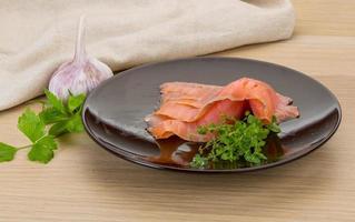 Sliced salmon on the plate and wooden background photo