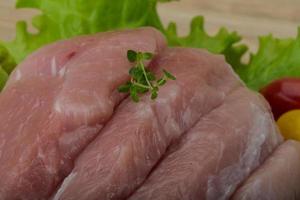 Schnitzel de cerdo crudo sobre tabla de madera y fondo de madera foto