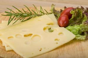 Maasdam cheese on wooden board and wooden background photo