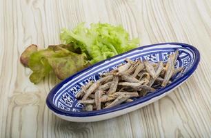 Dries anchovy in a bowl on wooden background photo