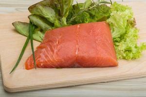 Salmon fillet on wooden board and wooden background photo