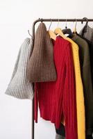 Row of different colorful Knitted sweaters hang on hangers, white background photo