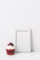 Art photo frame mockup with cup of coffee and cupcake, white background