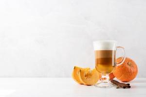 Latte de especias de calabaza en una taza de vidrio con canela foto