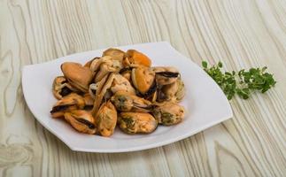 Mussels on the plate and wooden background photo