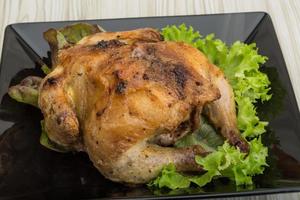 pollo asado en el plato y fondo de madera foto