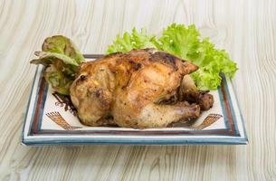 Roasted chicken on the plate and wooden background photo