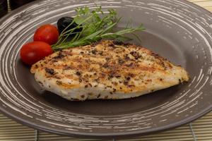 Grilled chichen breast on the plate and wooden background photo